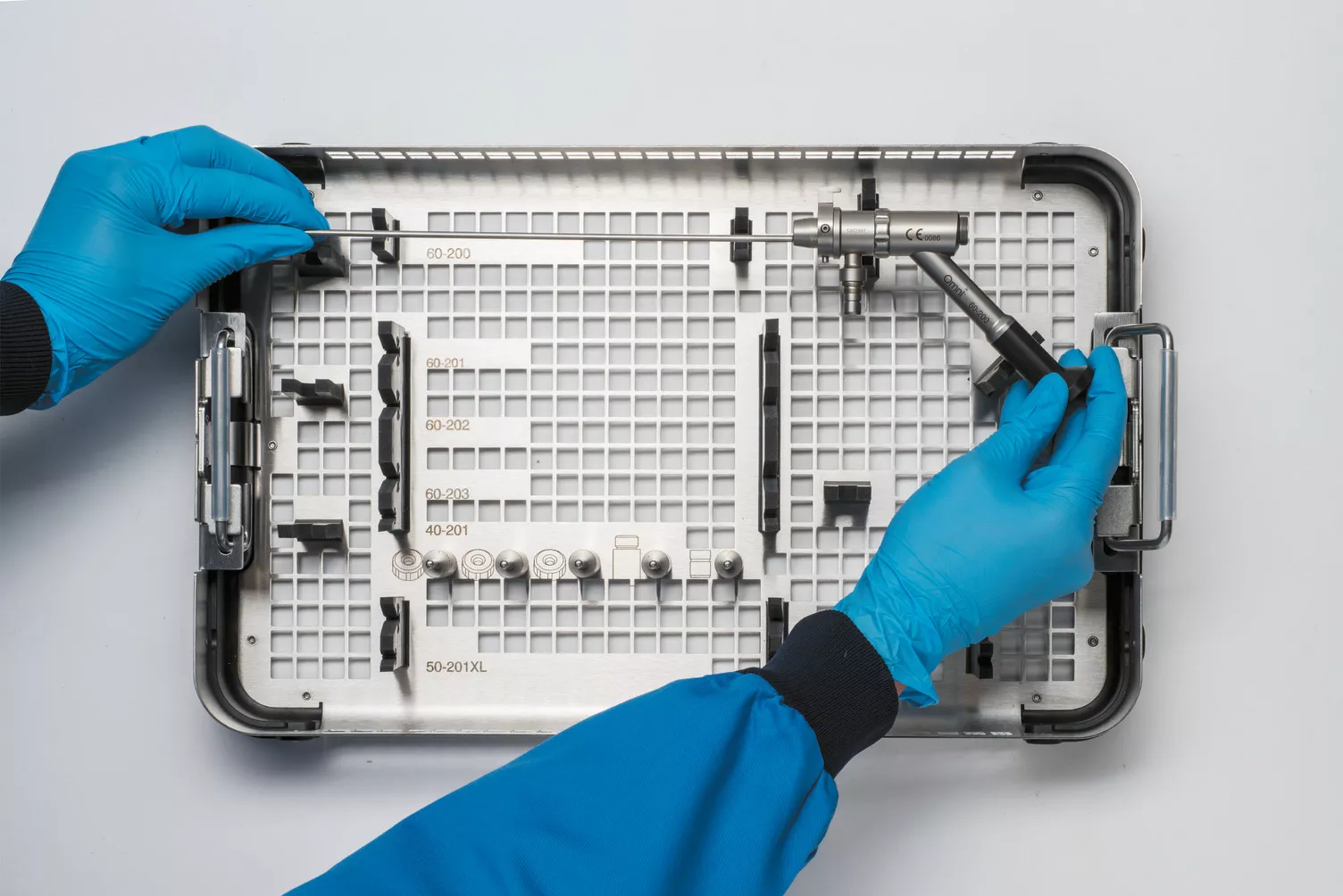 Handskbeklädda händer arbetar med en medicinsk bricka på ett bord.