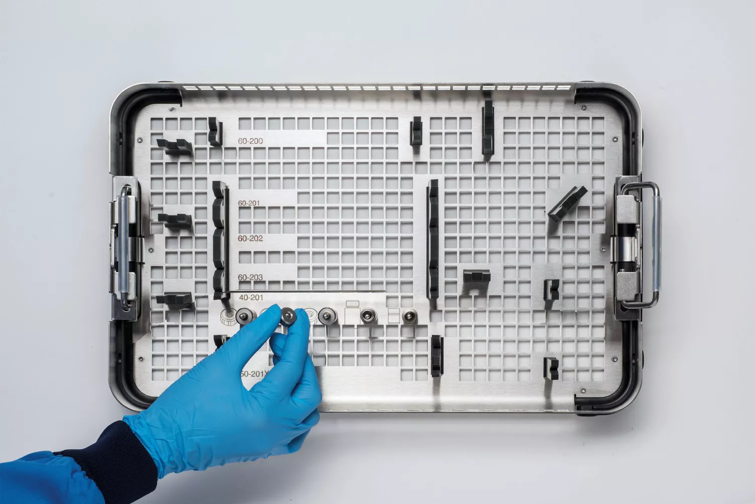 Handskbeklädd hand arbetar med en medicinsk bricka på ett bord.